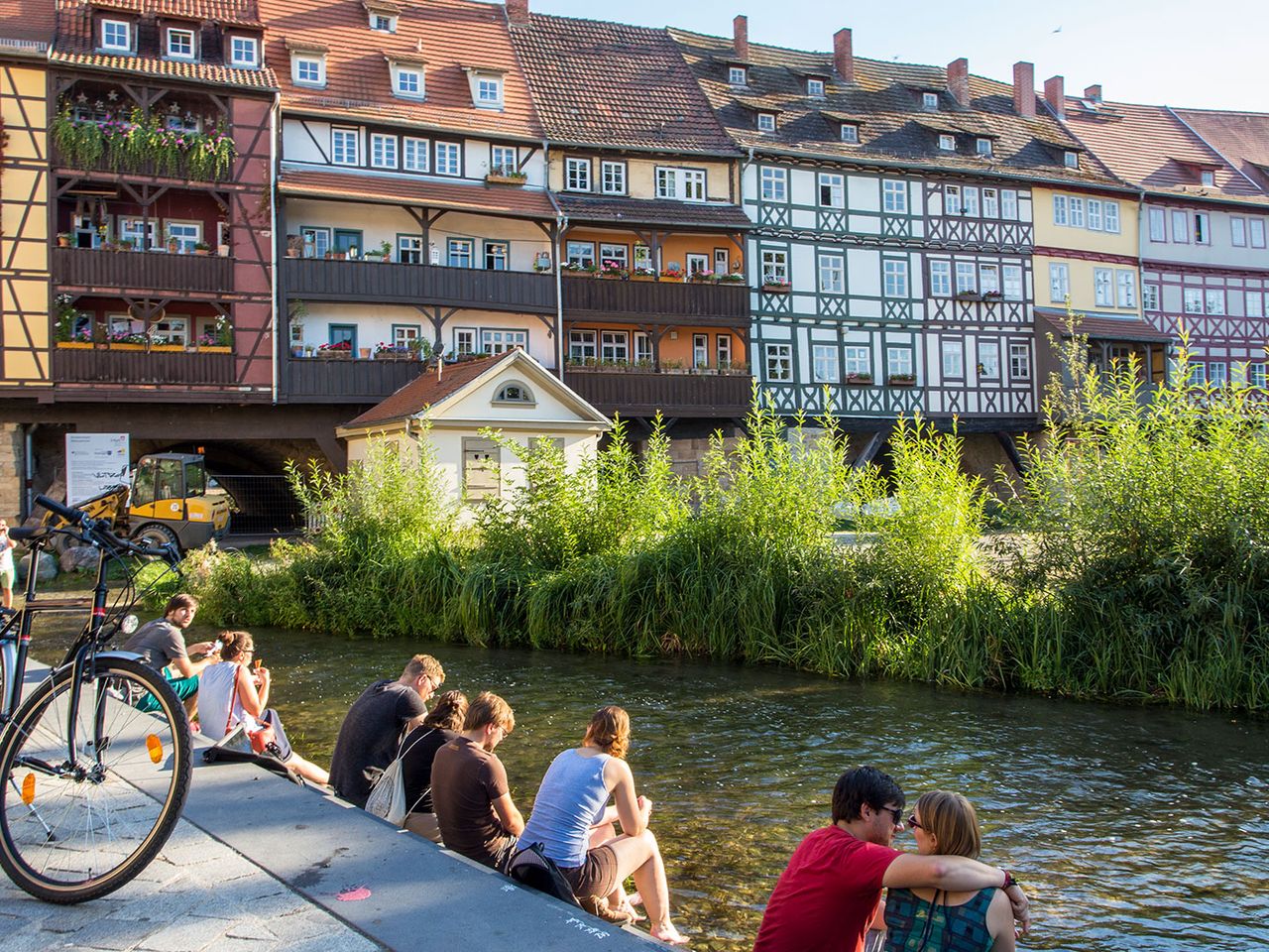 Menschen sitzen zu Füßen der Krämerbrücke in Erfurt
