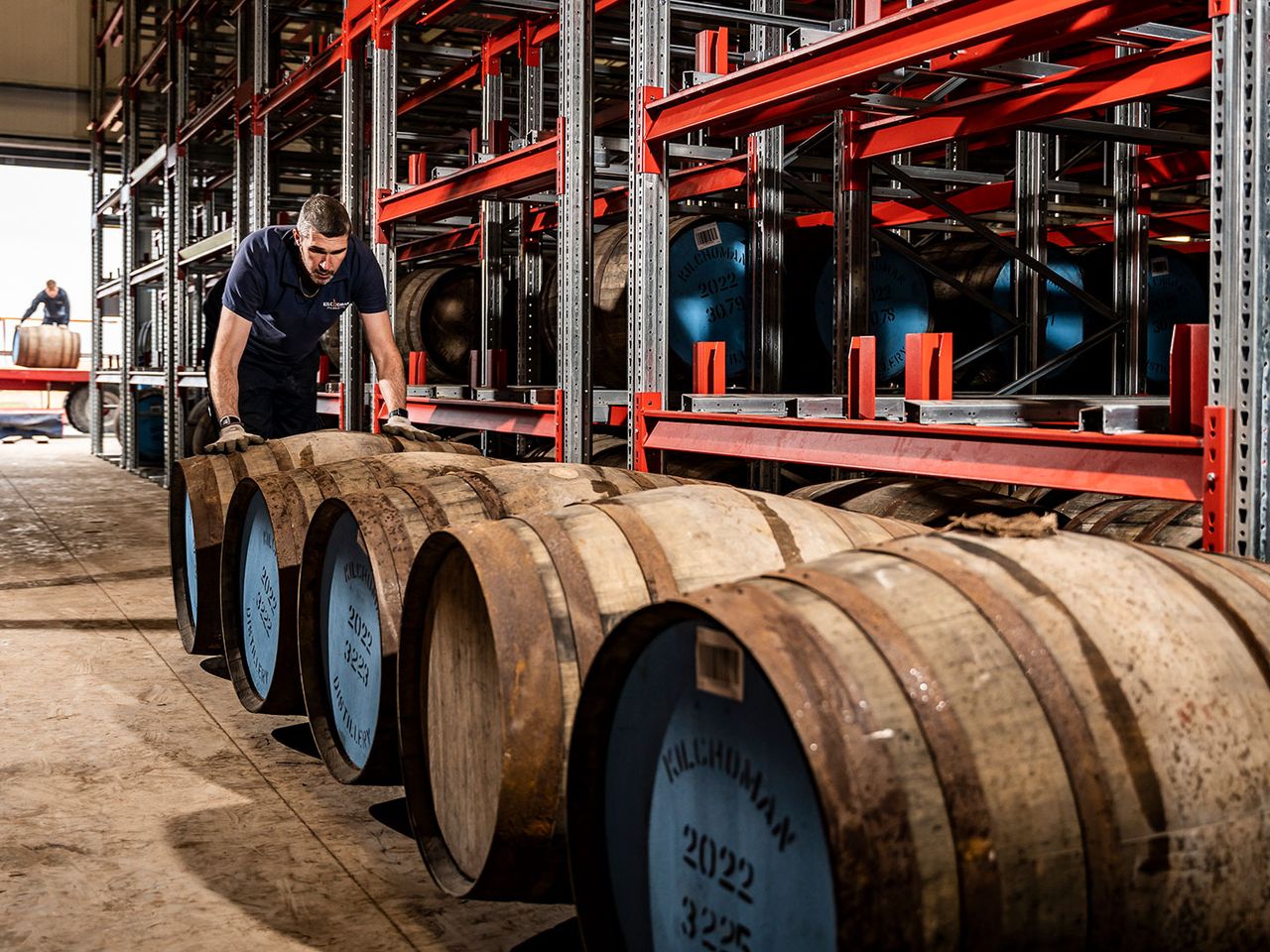 Mitarbeiter rollt Whisky-Fässer in der Kilchoman-Destillerie