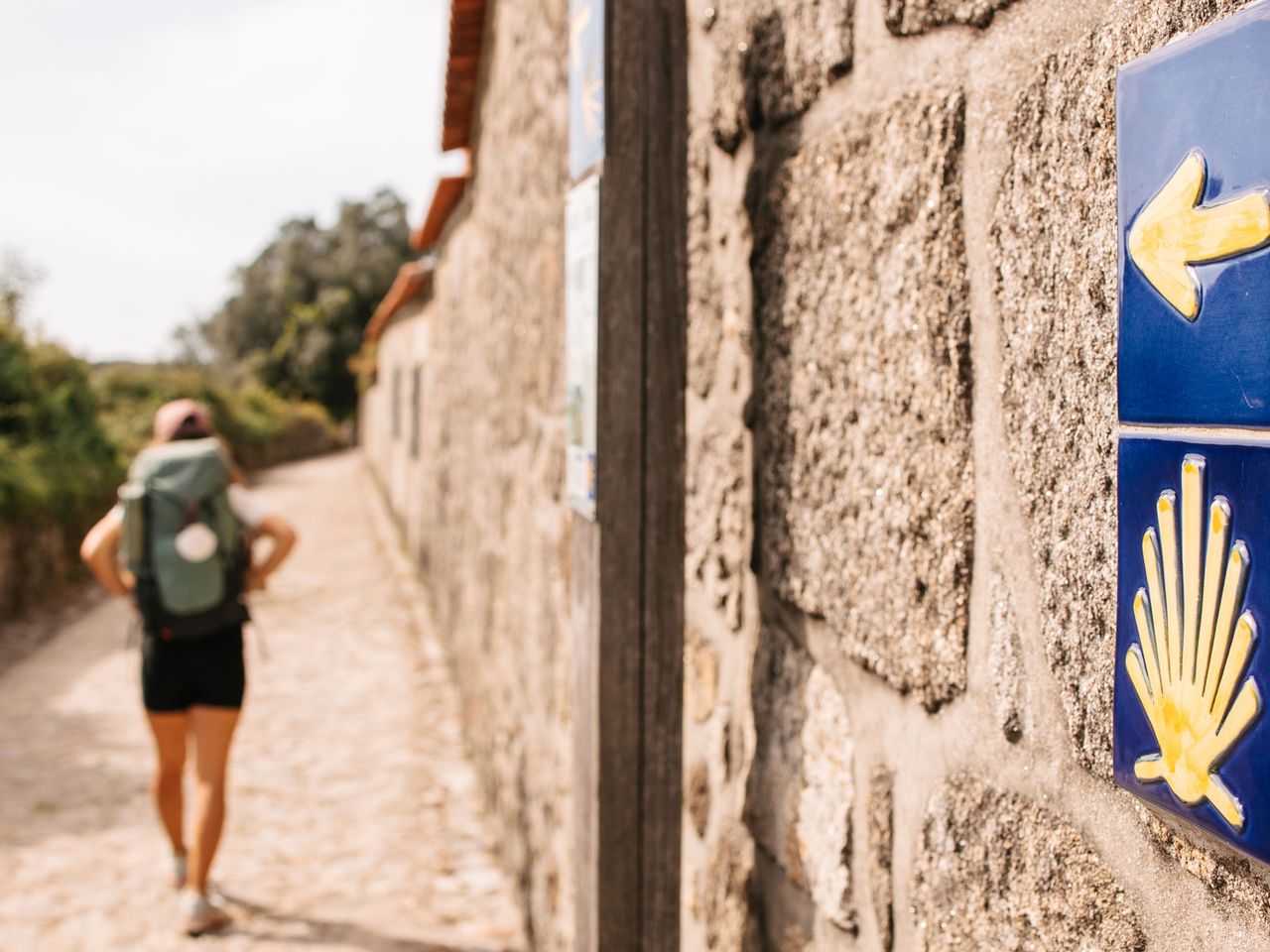 Person wandert auf dem Jakobsweg in Portugal, Muschel-Wegweiser