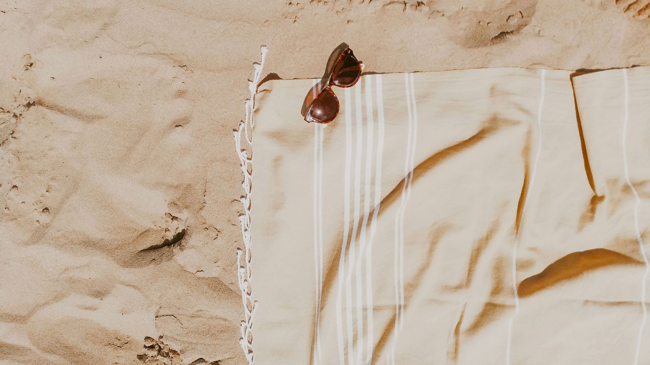Handtuch und Sonnenbrille am Strand