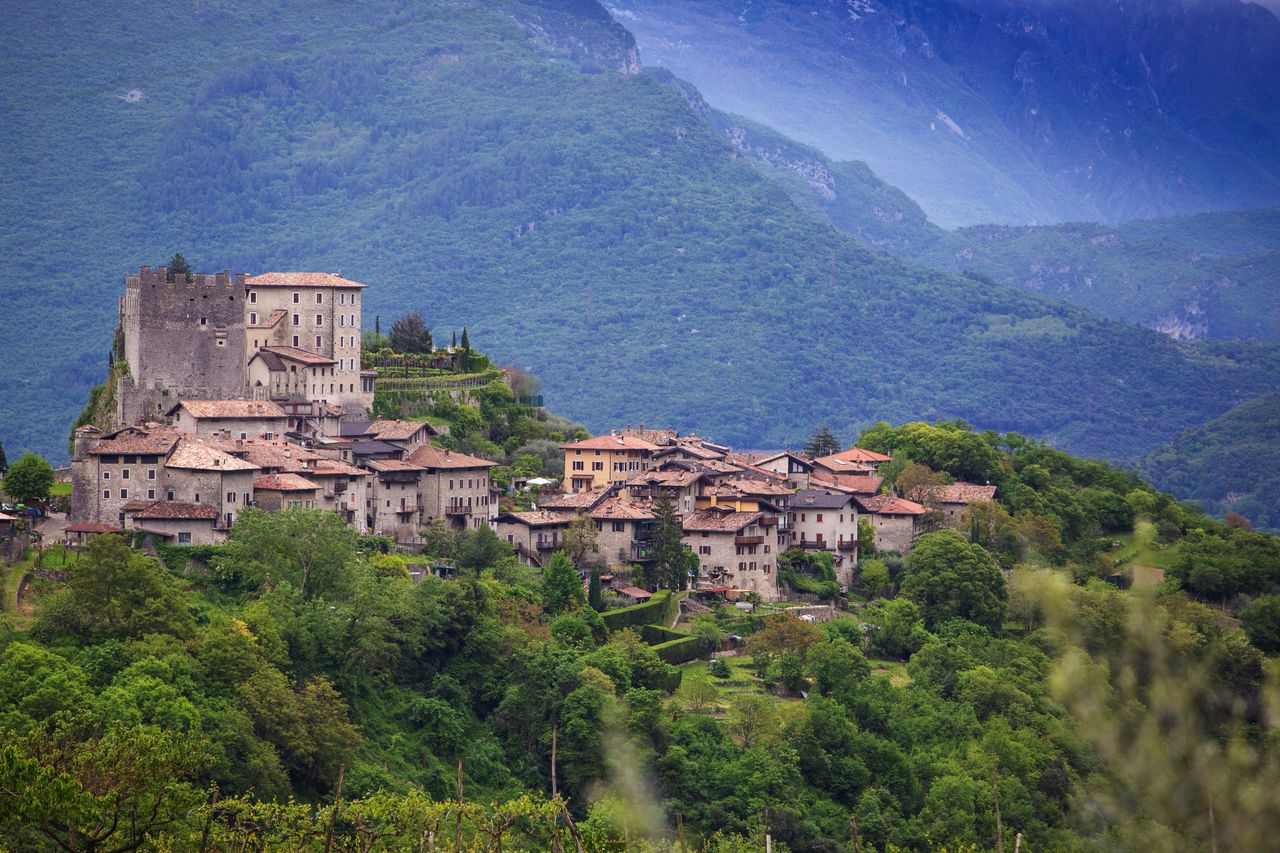 Seasons_13187688_HiRes_Blick_auf_das_Dorf_Tenno_in_der_Landschaft_des_waldreichen_Trentino_Italien