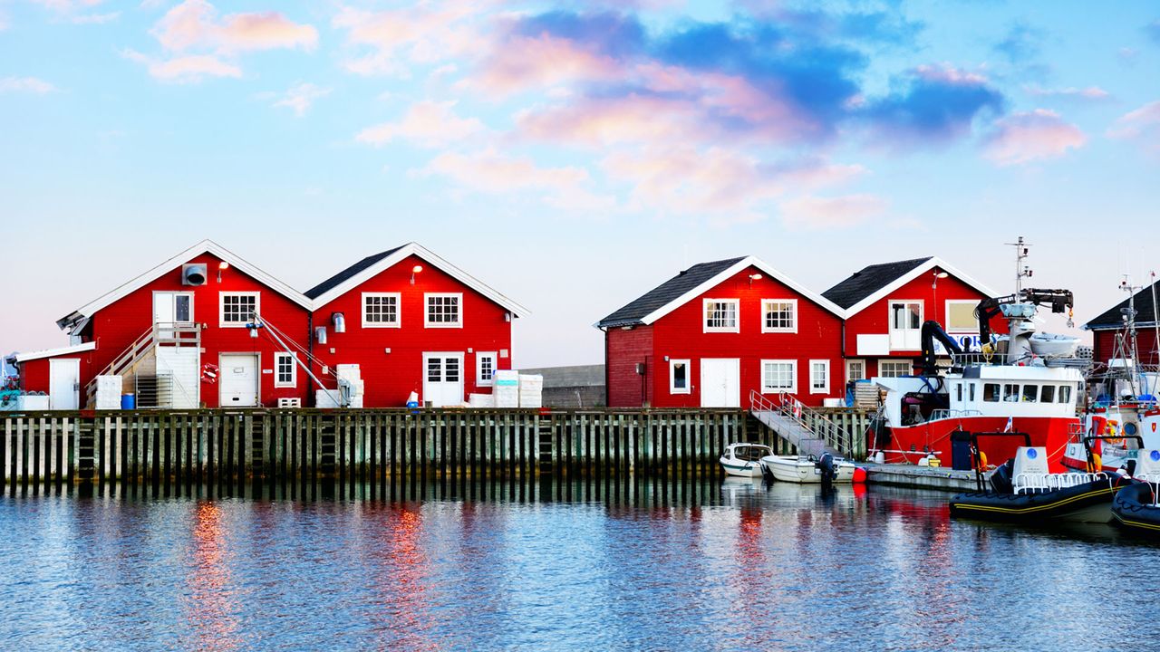 rote Holzhäuser und ein Boot am Hafen von Bodø
