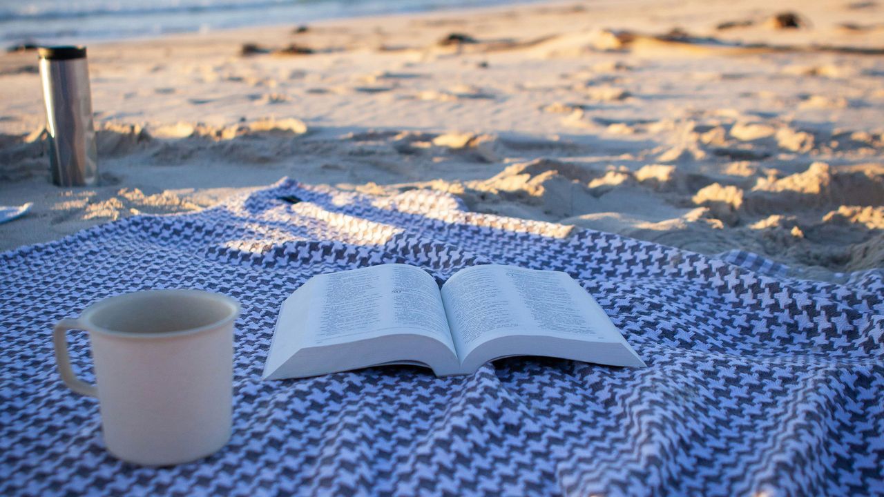 Buch und Kaffeetasse am Strand