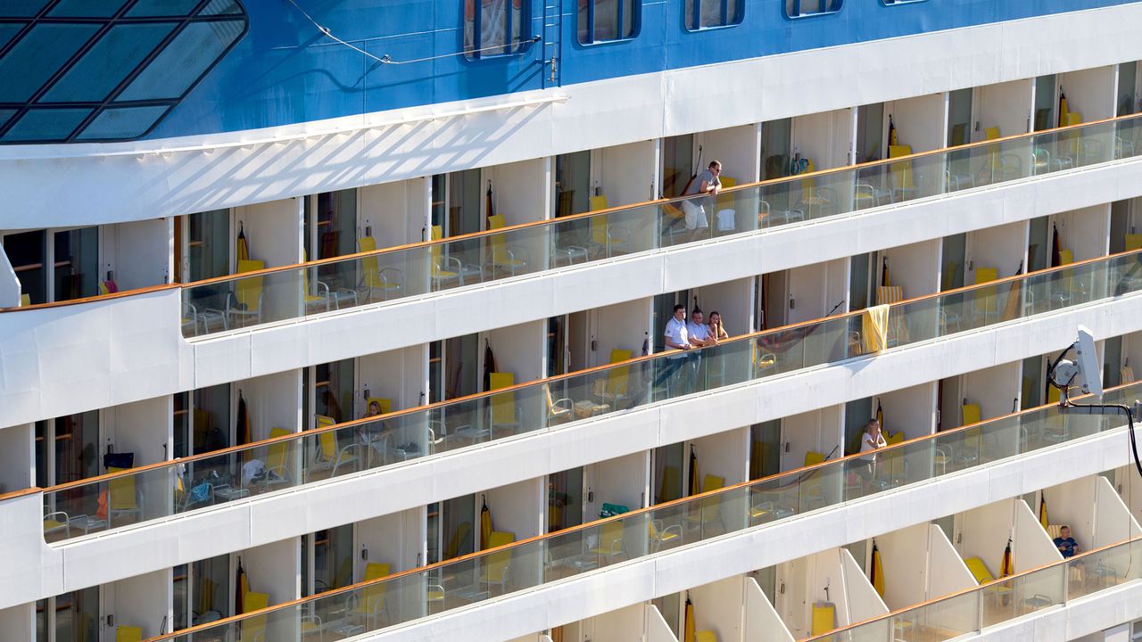 Menschen stehen auf den Balkonen eines Kreuzfahrtschiffs