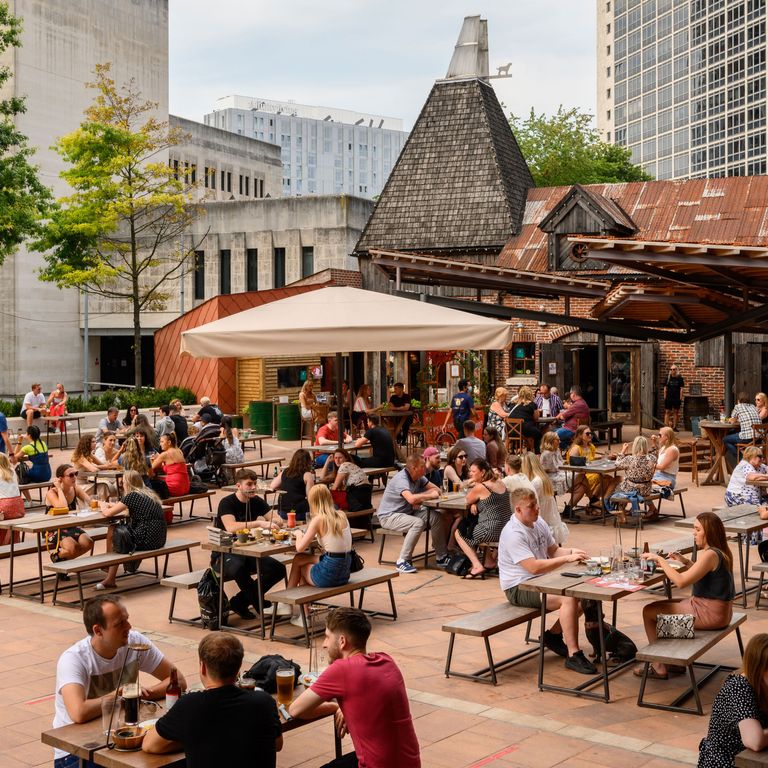 Menschen sitzen draußen im Viertel Spinningfields, Manchester