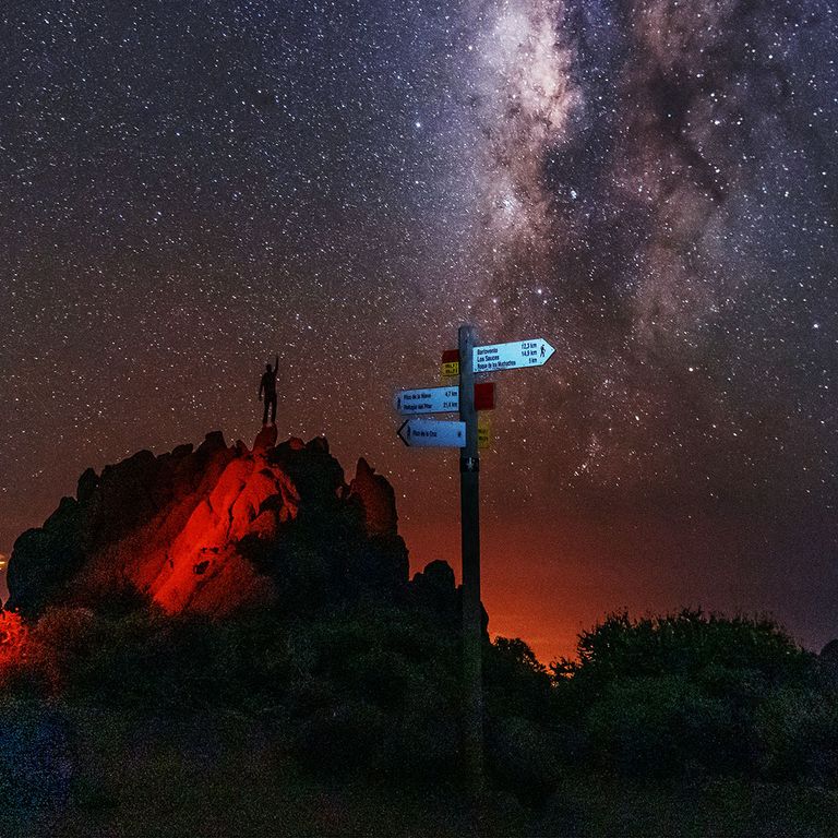Person blickt von einem Felsen aus auf die Milchstra&szlig;e